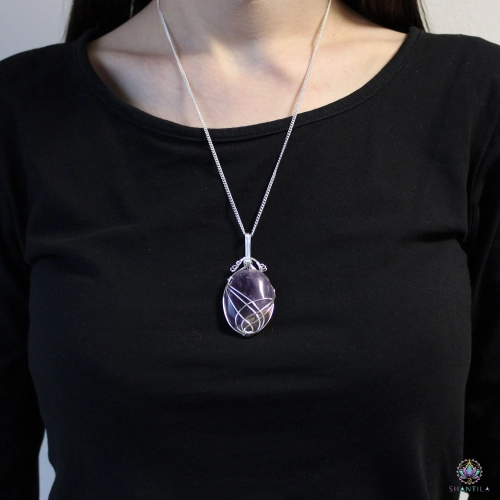Pendentif Améthyste Serti en Volutes — Chaîne 50 cm 2 Pendentif en améthyste serti en volutes porté sur un haut noir, le pendentif tombant sous les clavicules