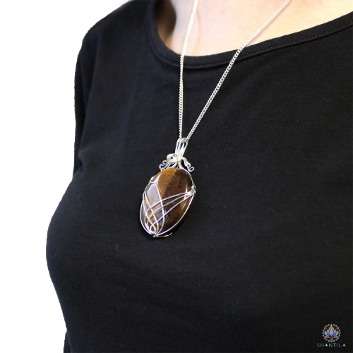 Pendentif Œil de Tigre Serti en Volutes — Chaîne 50 cm 4 Pendentif en œil de tigre serti en volutes porté sur un haut noir, le pendentif tombant sous les clavicules