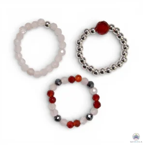 Trio de bagues élastiques en pierres naturelles — quartz rose et rubis — présentées côte à côte sur fond neutre, avec perles argentées, dans une palette de rose poudré et de rouge profond.