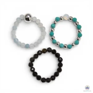 Trio de bagues élastiques en pierres naturelles — aigue-marine, turquoise et obsidienne noire — présentées sur fond neutre avec perles argentées, dans une palette de bleu translucide, bleu-vert et noir profond.