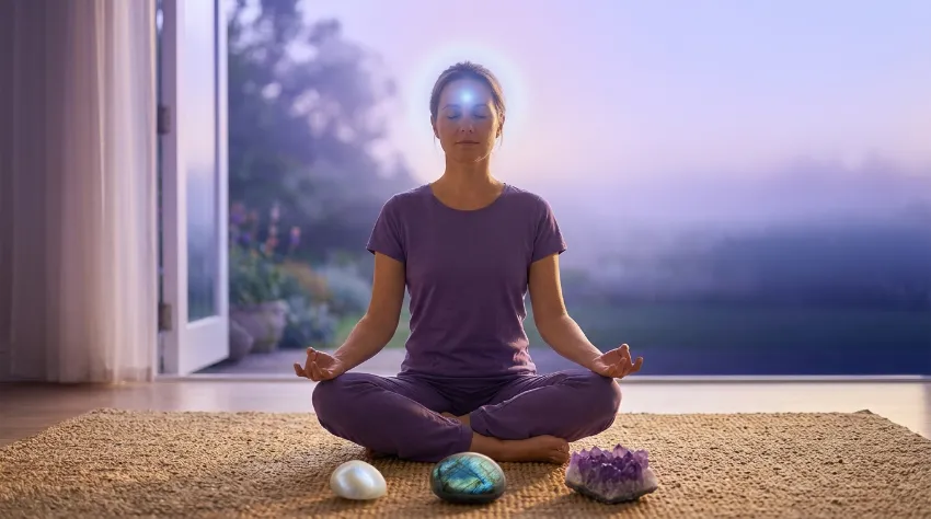 Pierres pour le chakra du troisième œil : intuition et clarté mentale 1 Silhouette en méditation entourée de pierres pour le chakra du troisième œil (améthyste, labradorite, pierre de lune)